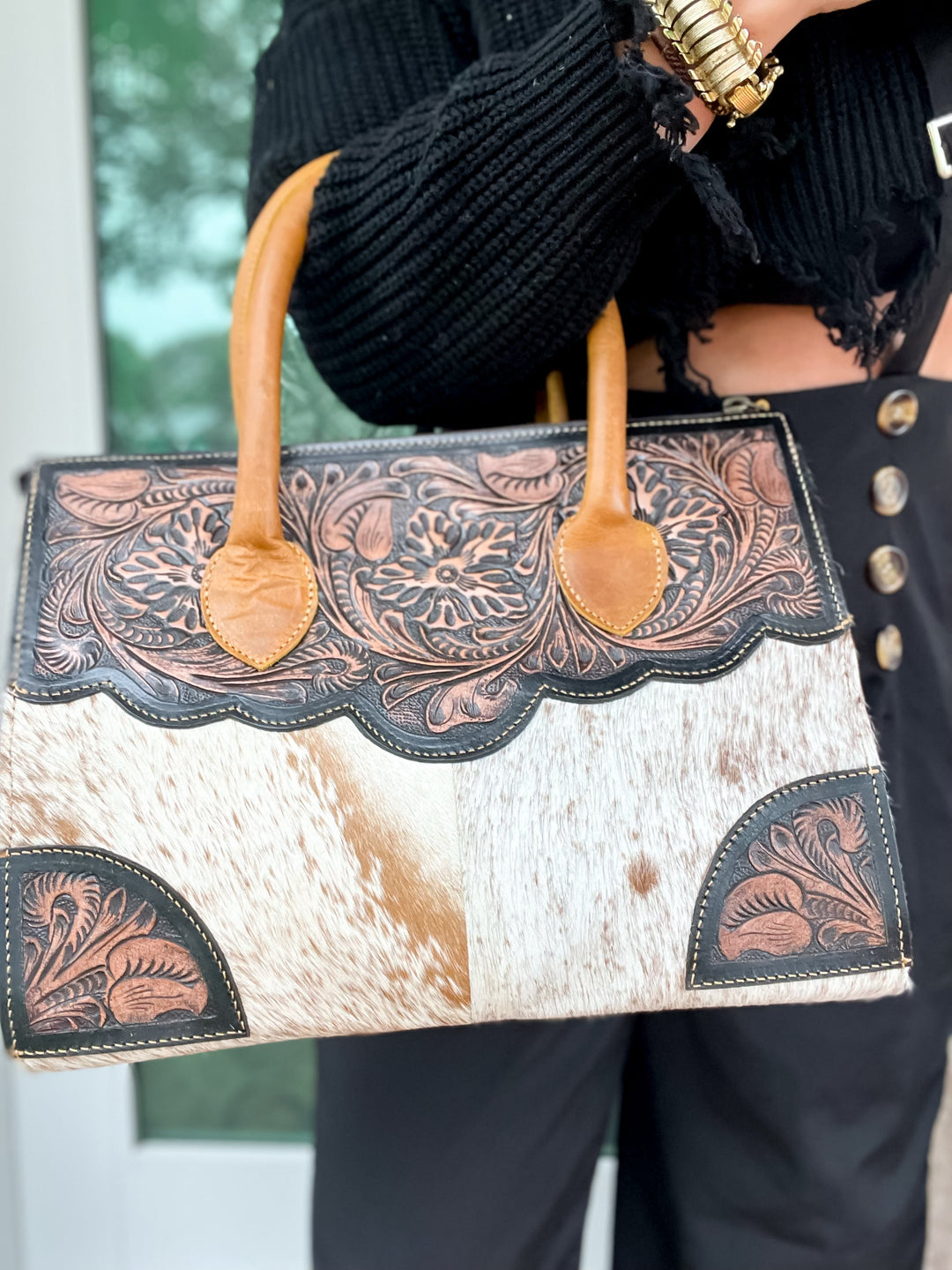 Holding a cowhide and leather concealed carry purse in front of door