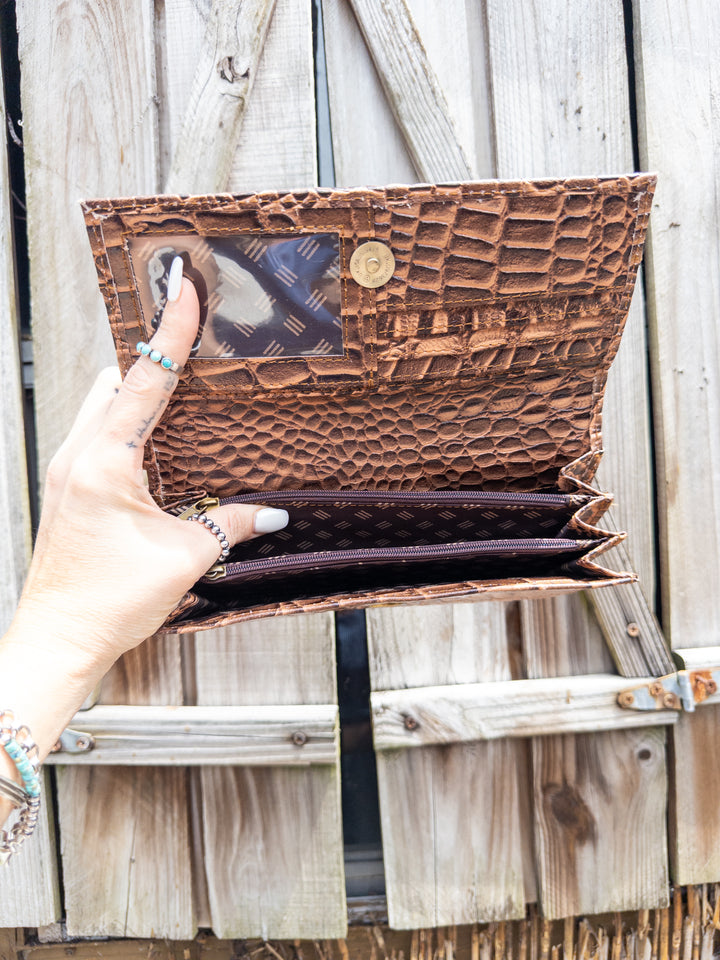 Inside of embossed leather clutch wallet showing card slots, zipper pocket, and compartments.