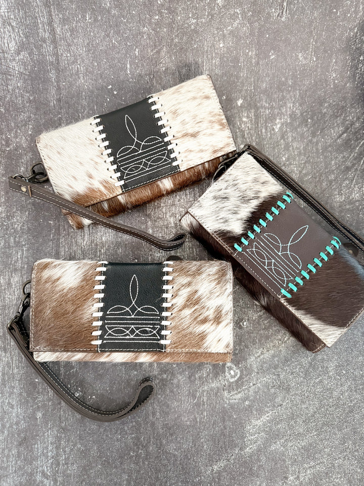 Three cowhide wallets with unique patterns on a gray surface