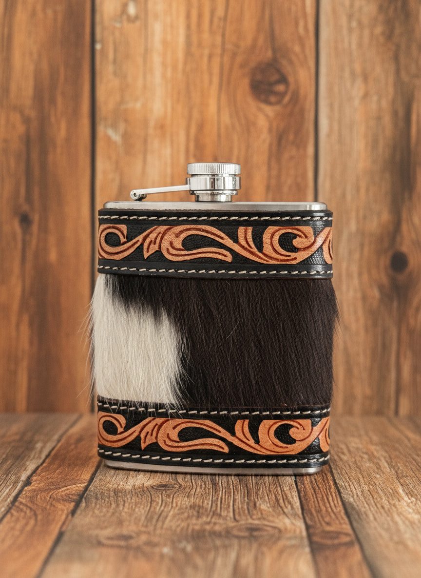 A hand-tooled leather and cowhide flask with intricate tooled patterns