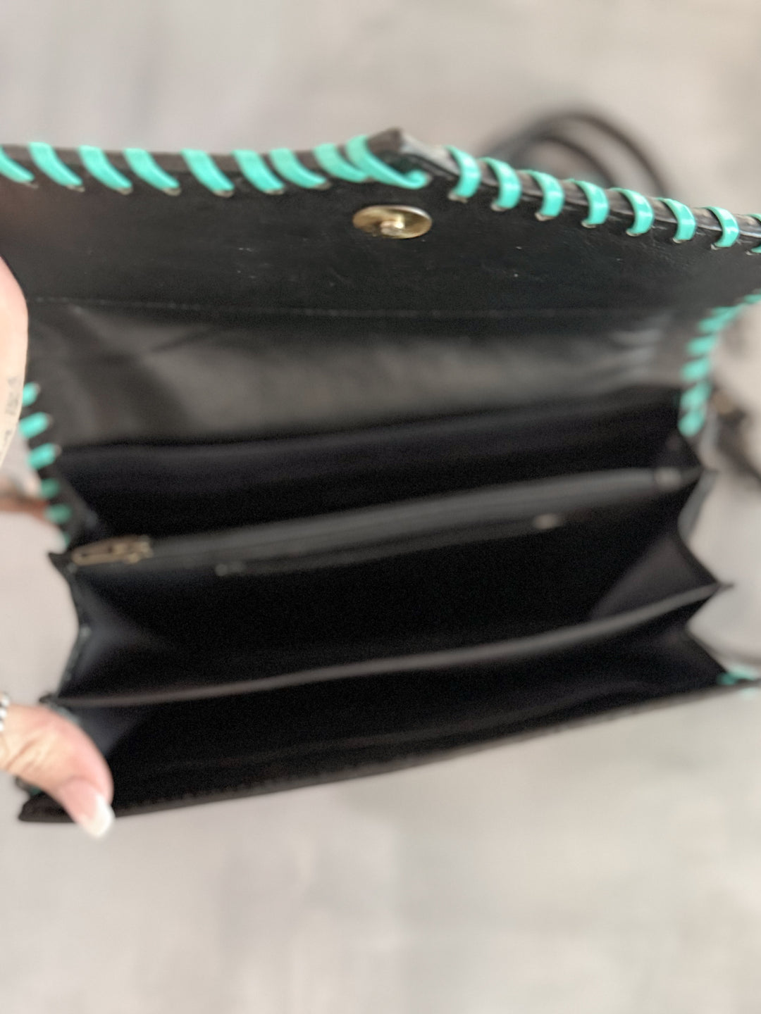 Interior view of wallet-style tooled leather clutch with compartments, zipper pocket, and phone slot