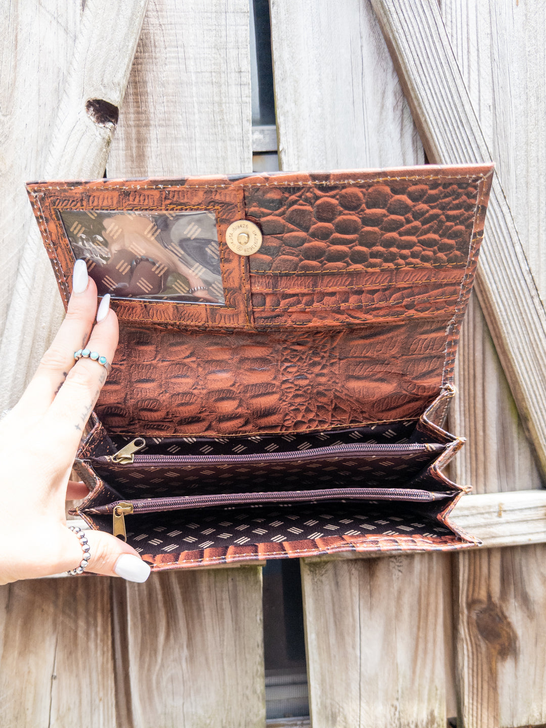 Inside of embossed leather clutch wallet showing card slots, zipper pocket, and compartments.