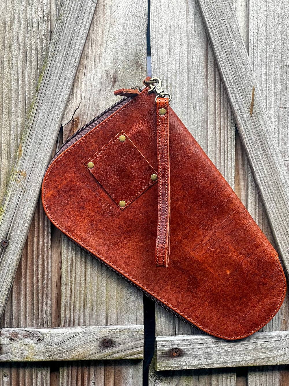 Backside photo of the tooled leather and cowhide handgun case with hand strap and belt loop