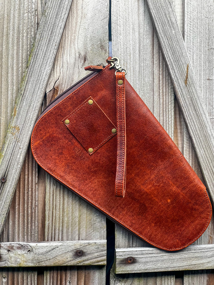Backside photo of the tooled leather and cowhide handgun case with hand strap and belt loop