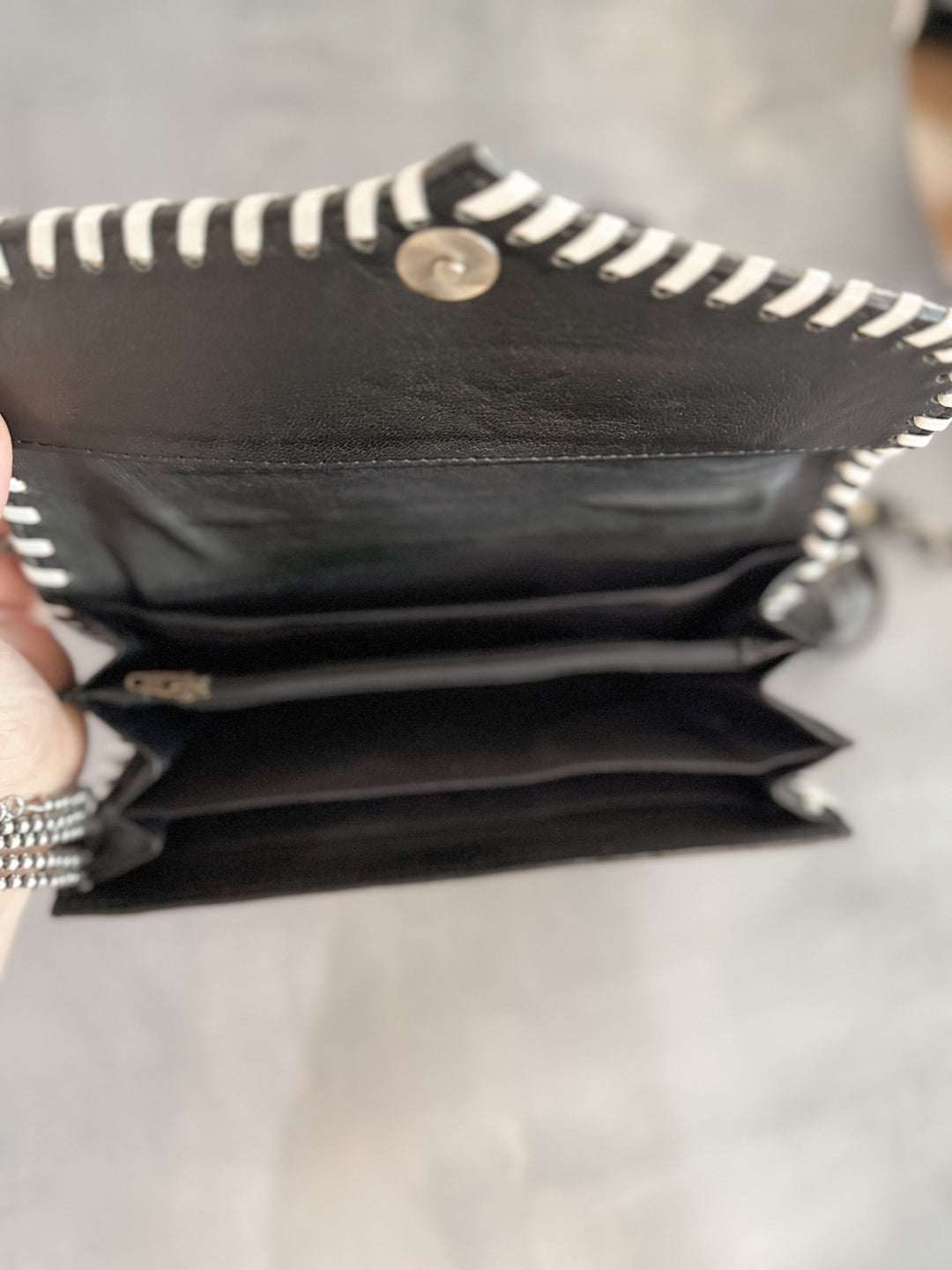Interior view of wallet-style clutch with multiple compartments, zipper pocket, and phone slot