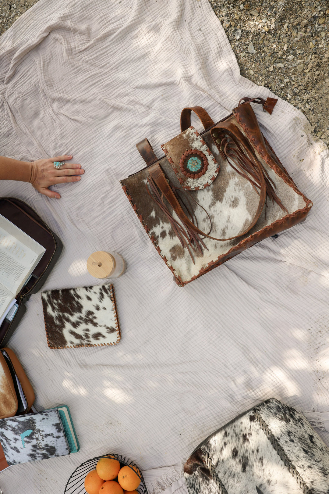 Cowhide leather tote and cowhide Bible cover styled on a blanket outdoors with oranges and sunlight — Western-edge meets old Florida soul.