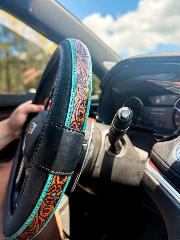 Black and turquoise tooled leather Western steering wheel cover in vehicle interior