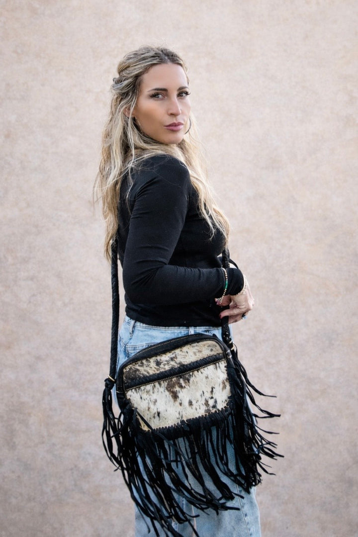Side view of black cowhide fringe crossbody worn crossbody
