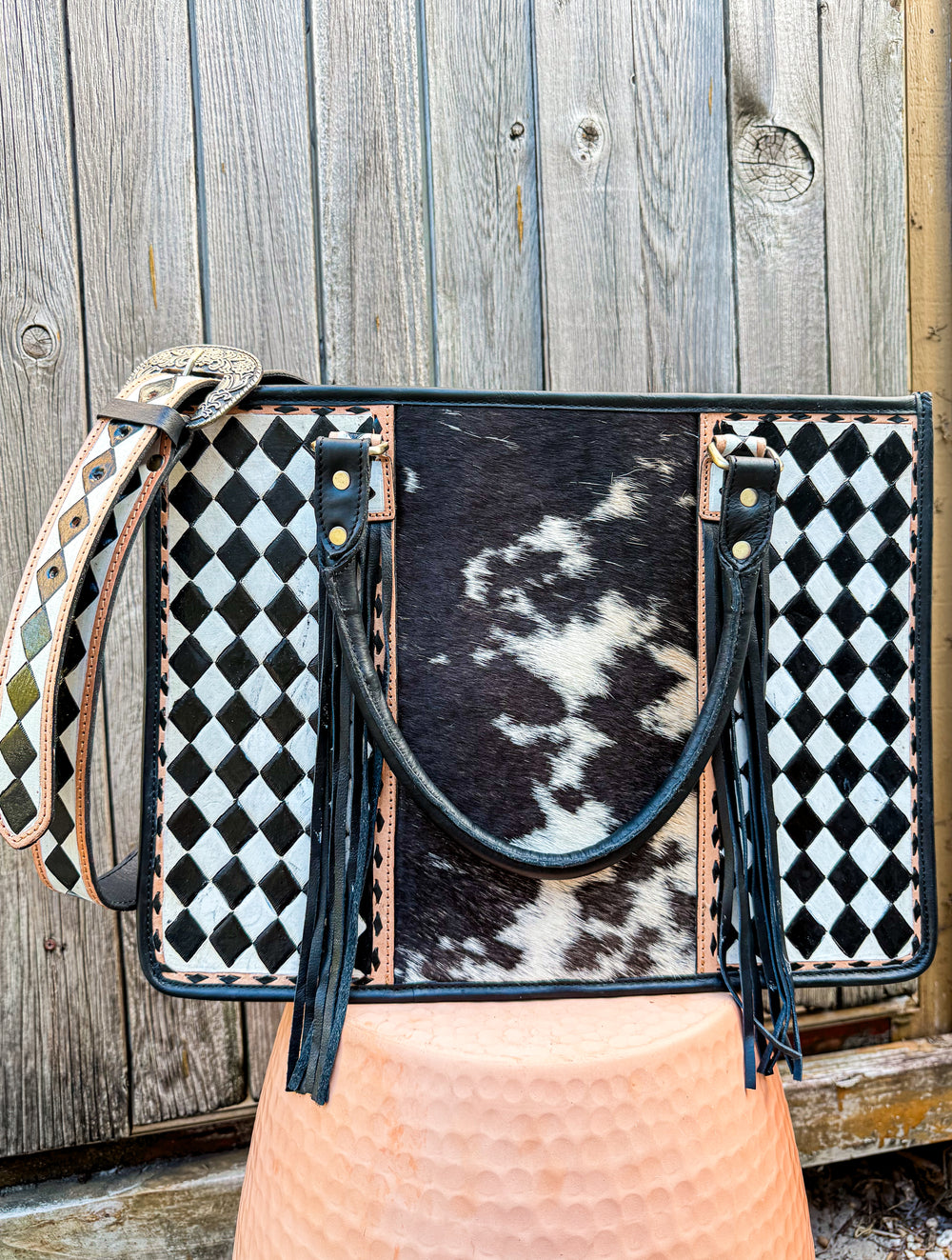 Handbag with black and white checkered pattern and cowhide leather on a wooden background