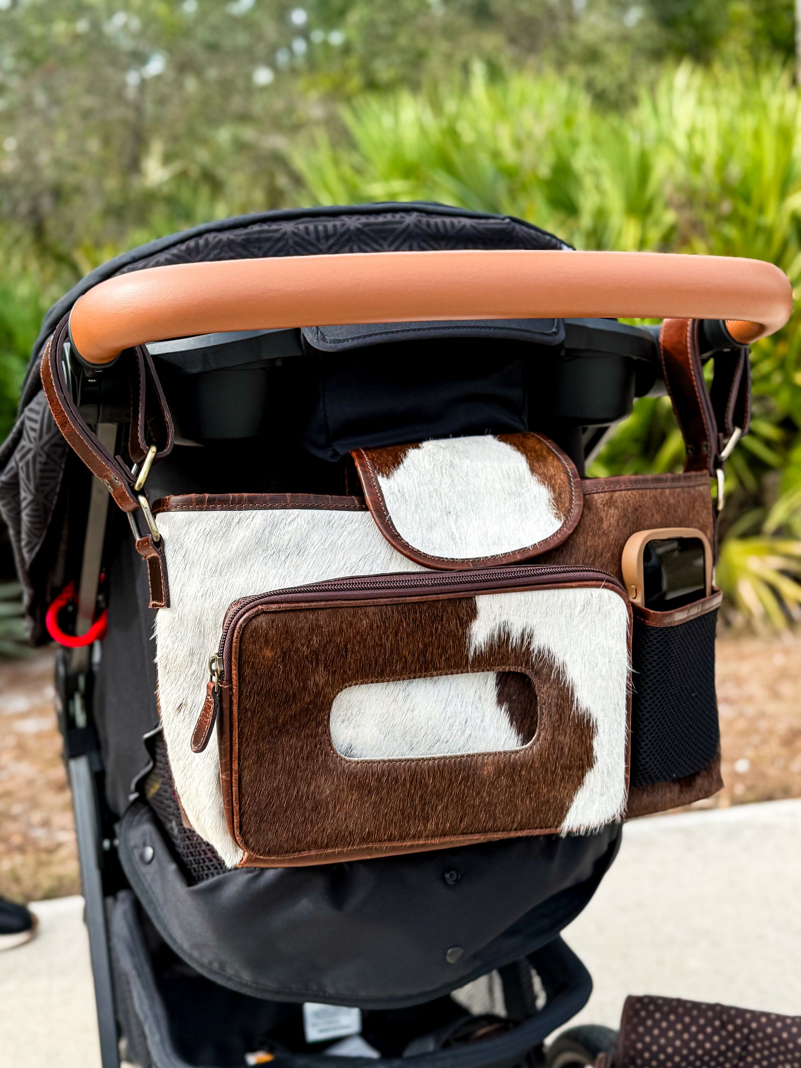 Stroller with a brown and white hair on cowhide all leather diaper bag attached to the handle from East Coast Carry
