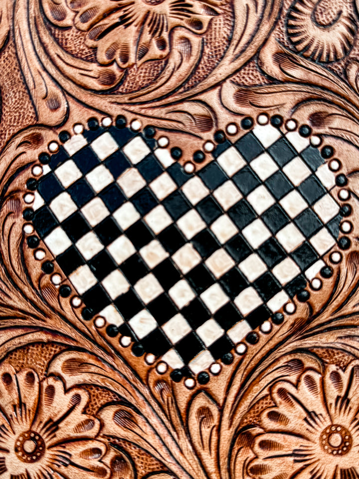 Close-up of tooled leather flap with black and white checkered heart detail on western fringe purse