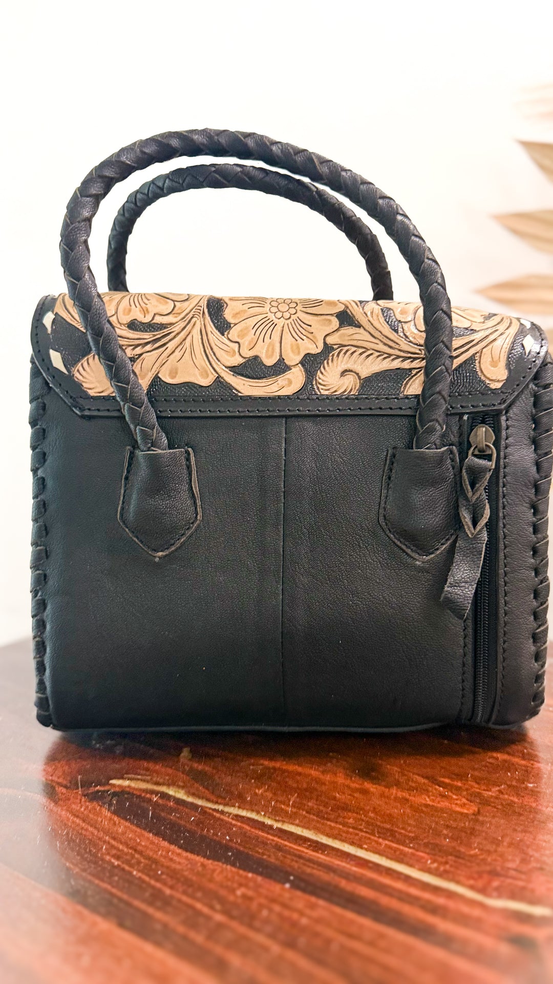 Back of The Ranch Wife Carryall Mini showing black leather, braided handles, exterior zipper pocket and floral tooled leather flap.