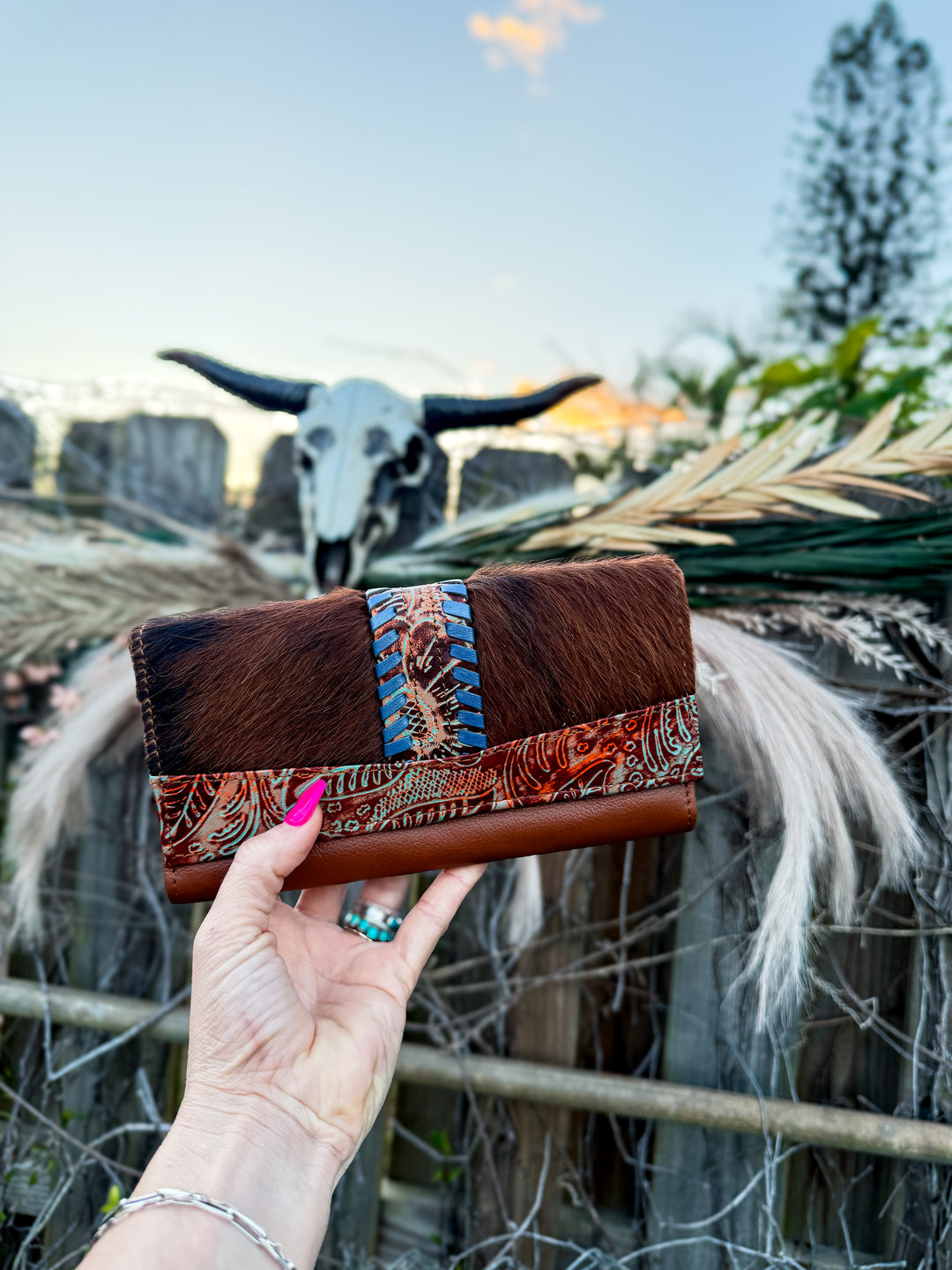 Brown leather cowhide phone clutch with turquoise detailing and purple whip-stitching 