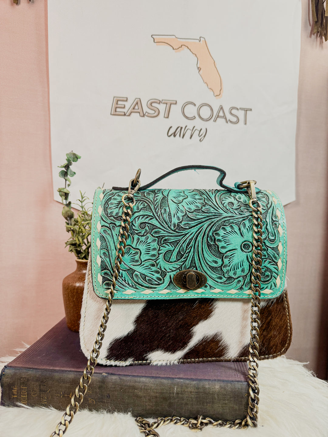 Coastal Hide turquoise tooled leather and brown-and-white cowhide chain satchel purse with bronze hardware from East Coast Carry.