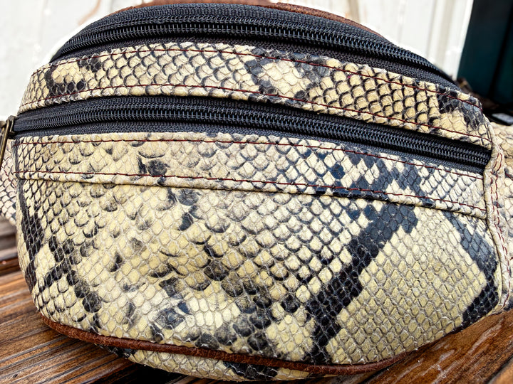 Butter yellow snake print genuine leather belt bag with adjustable strap and zipper pockets.