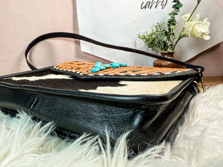 Bottom view of the Black leather handbag with floral tooled leather and Turquosie cactus western design elements on a white surface