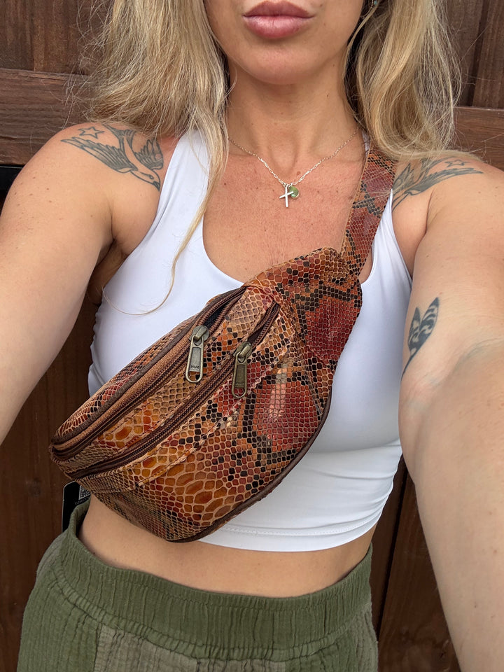 Woman wearing a genuine leather snake print belt bag crossbody style with western jewelry and neutral activewear.