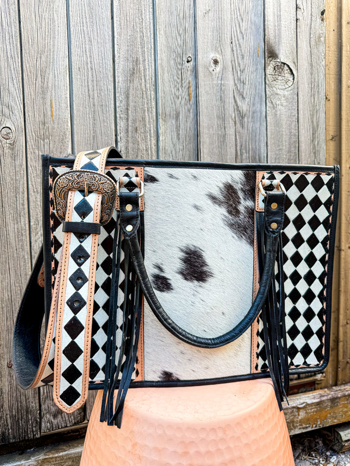 Concealed Carry Handbag with cowhide checkered leather and decorative strap against a wooden background