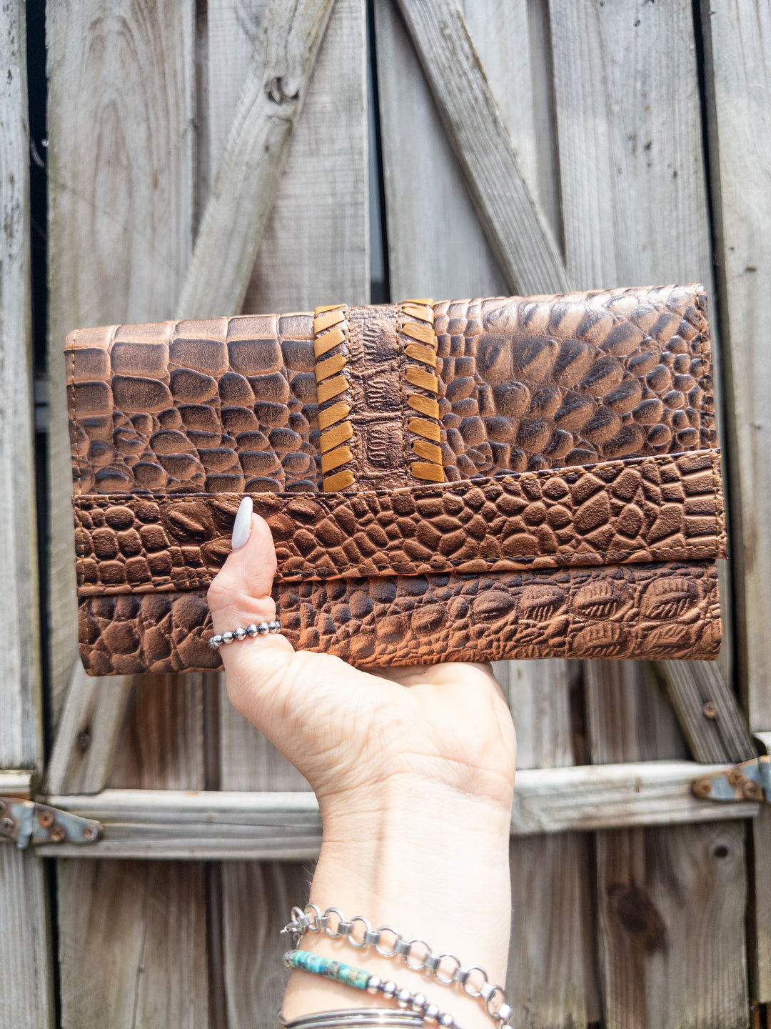 Embossed leather clutch wallet in croc-look pattern with bold yellow whipstitch detail, front view.