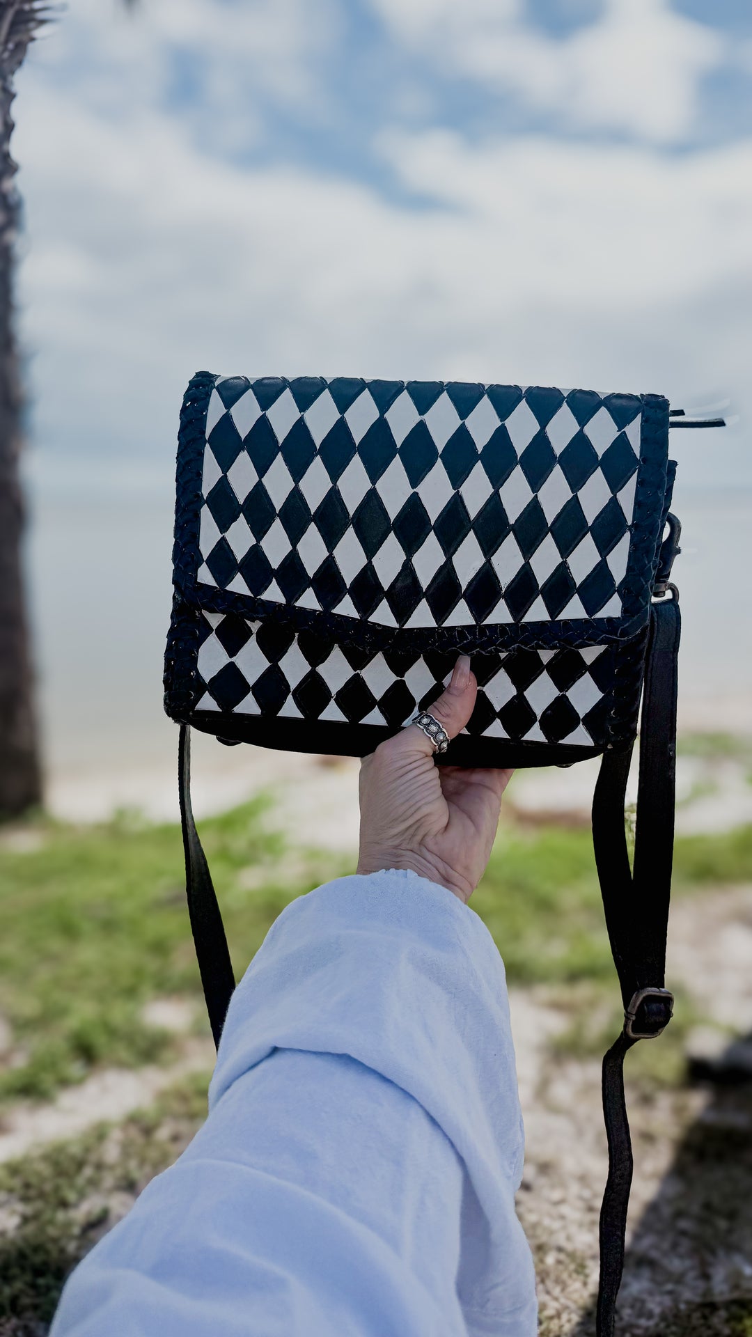 Black and white Western leather crossbody purse with adjustable black shoulder strap and bold diamond-check pattern.