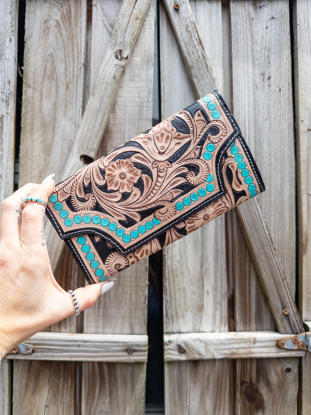Western wallet with hand-tooled floral leather, turquoise stud accents, and black detailing, front view.