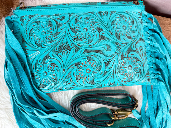 Back view of turquoise floral tooled leather crossbody with fringe sides