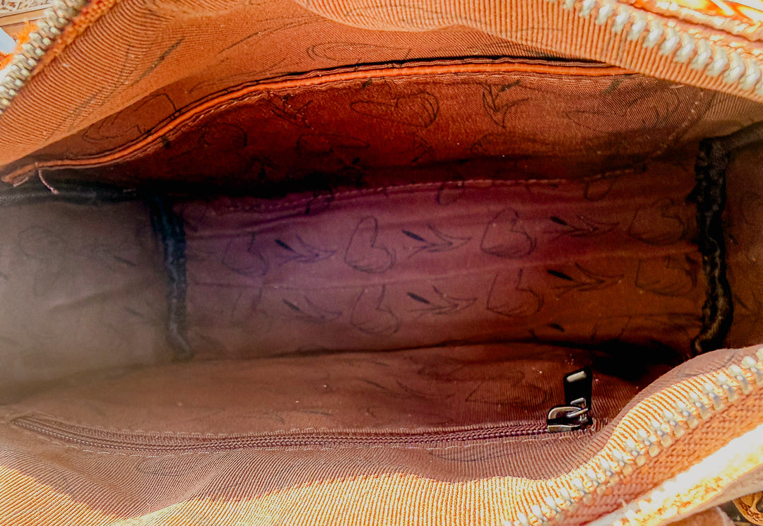 Close-up of the inside of brown leather bag with visible stitching and texture with inside pockets