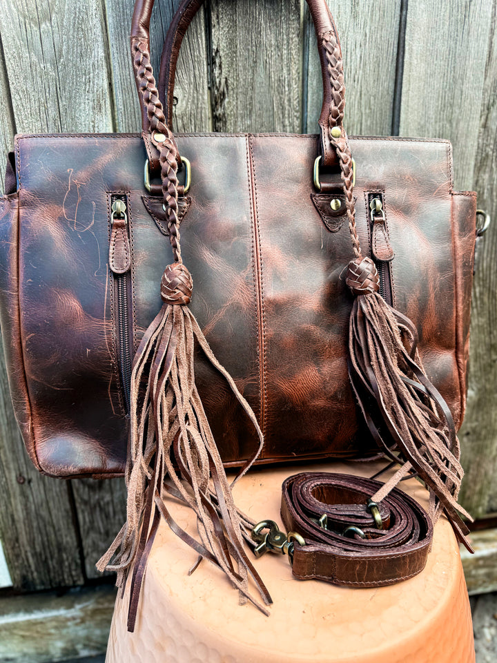Back view of brown leather tote with zipper pockets and braided handles