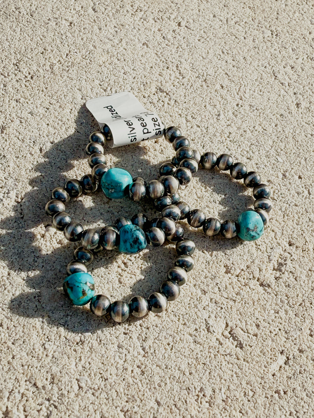 Graduated sterling silver desert pearl stretch rings with oxidized finish and Kingman turquoise on flat lay