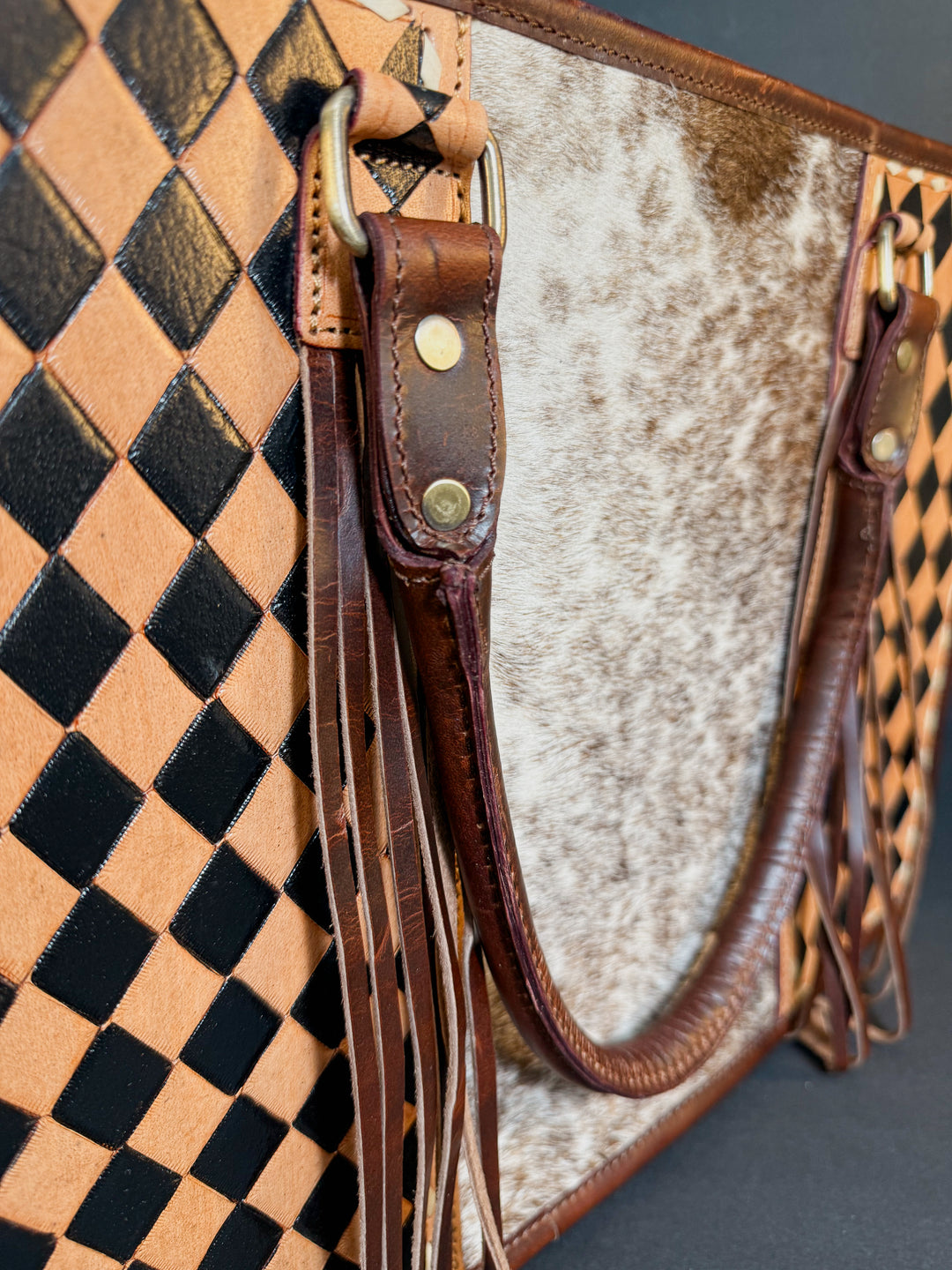 Close-up of brown checkered tooling and cowhide texture on full-grain leather tote.