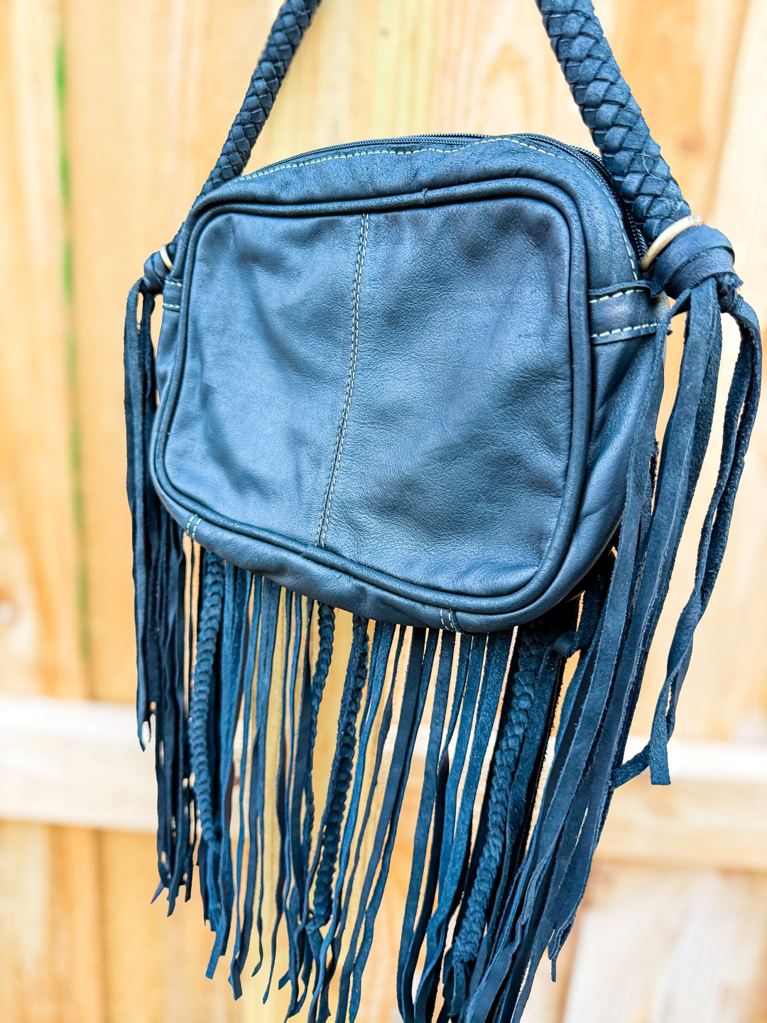 Back view of the Donna Jean Black cowhide fringe crossbody leather bag with braided leather strap