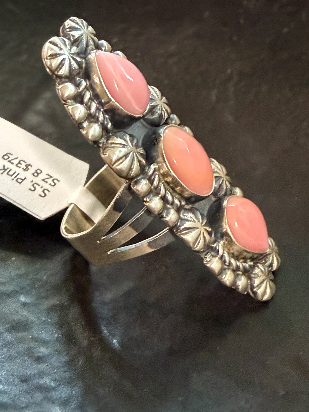 Side view of Navajo pink conch shell ring with sterling silver stamp work