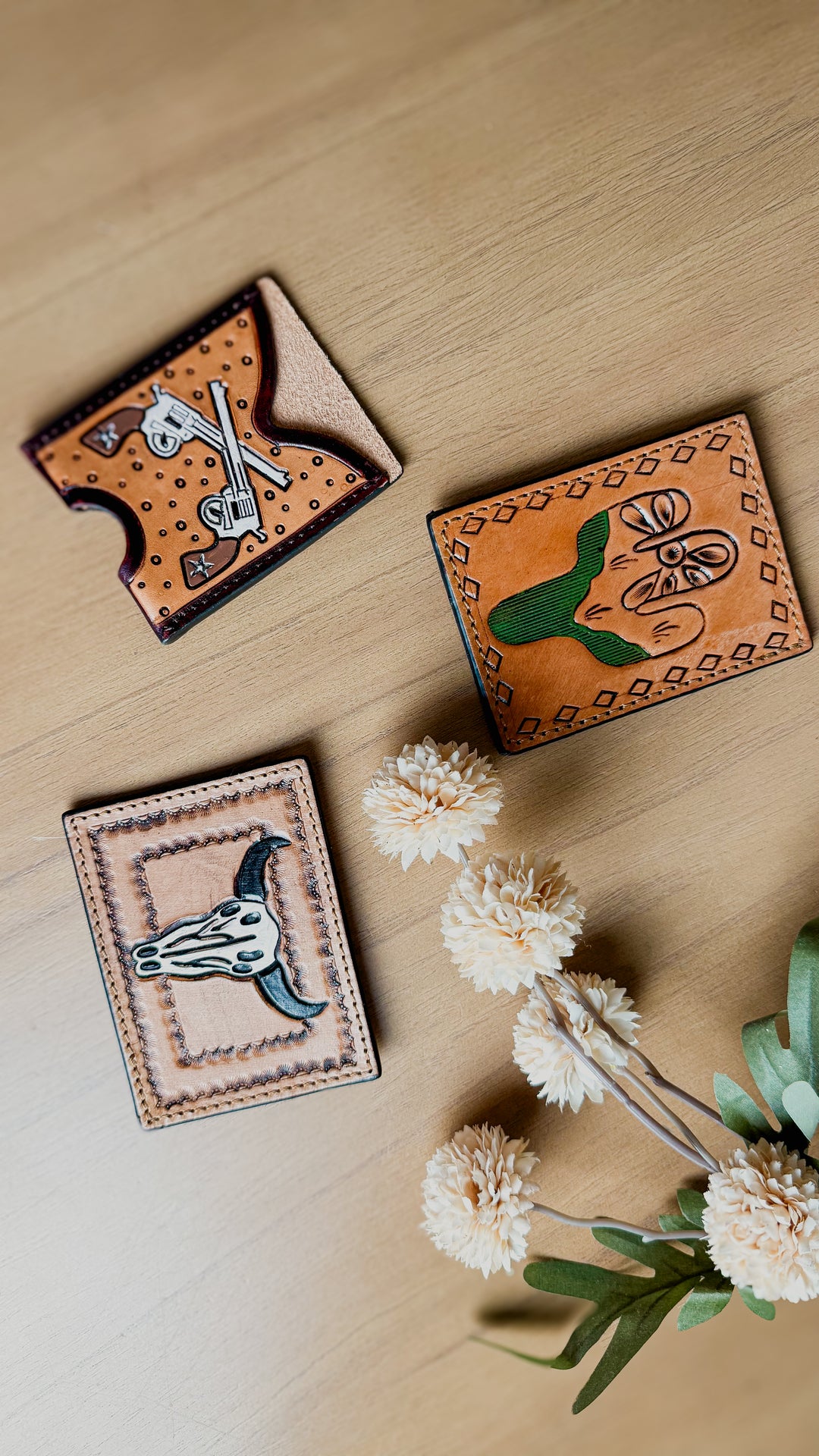 Genuine hand tooled leather western pocket card wallets featuring cow skull, cactus, and crossed pistols designs