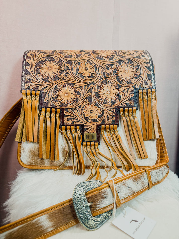 Large Work Messenger Handbag with floral tooled leather patterns and fringes on a white surface