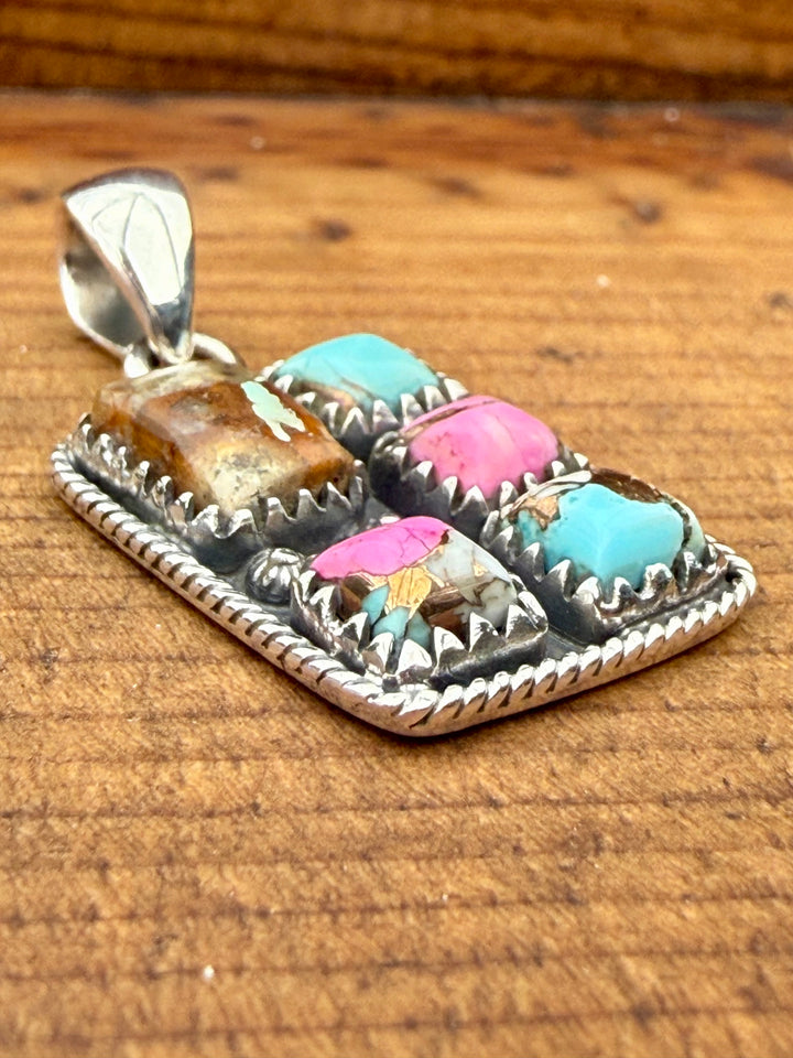 Sterling silver Mine #8 turquoise and pink composite southwestern pendant with stamped detailing and bale on wood background
