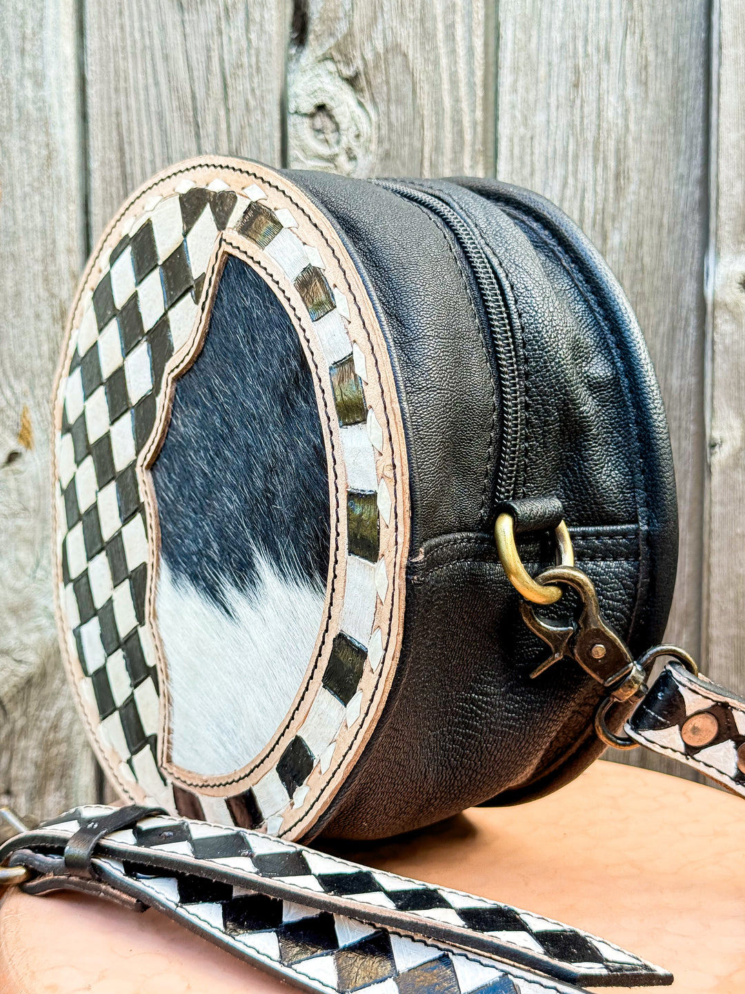 Side view of black leather round canteen purse with zip closure and brass hardware