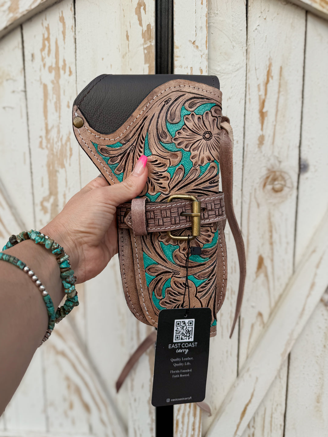 Handmade western revolver holster with floral tooled leather, turquoise painted accents, basketweave buckle detail, and leather tie straps for belt carry.