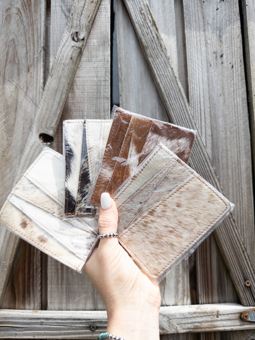 Genuine hair on cowhide card holder pocket sleeve held in hand showing four hide options