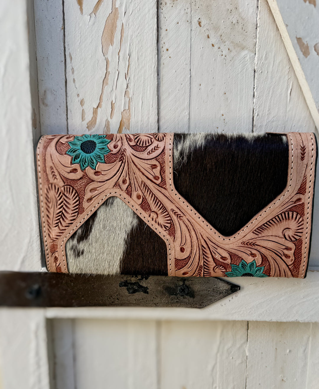 Back view of the Turquoise Bloom tooled leather cowhide wallet with turquoise flower accents and black and white hair on hide
