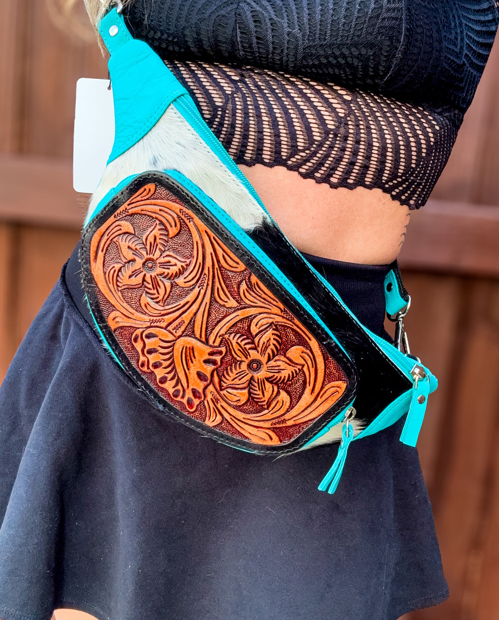 Person wearing a turquoise leather cowhide sling bag western tooled chest bag crossbody
