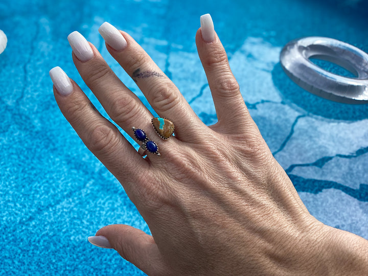 Hand wearing a Sterling silver adjustable floater ring with turquoise and lapis southwestern statement jewelry against a blue pool background