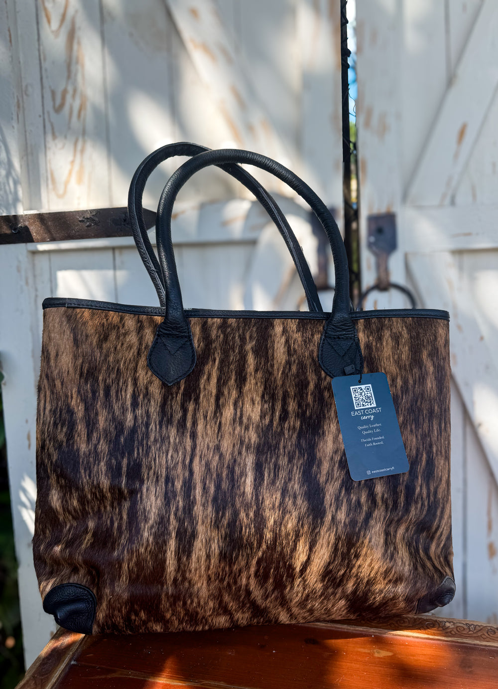 Brindle hair-on cowhide tote bag with black leather handles and structured shape