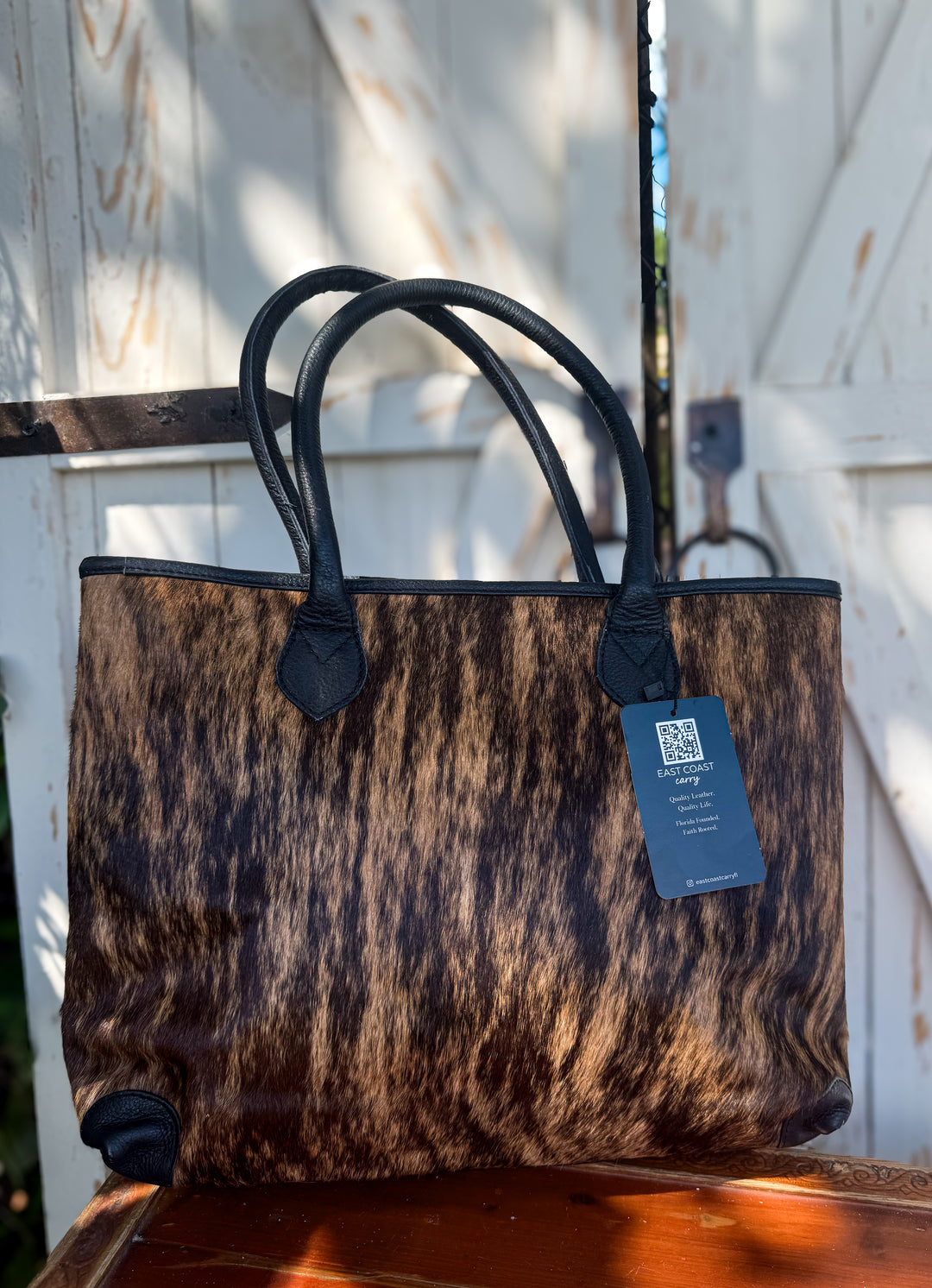 Brindle hair-on cowhide tote bag with black leather handles and structured shape