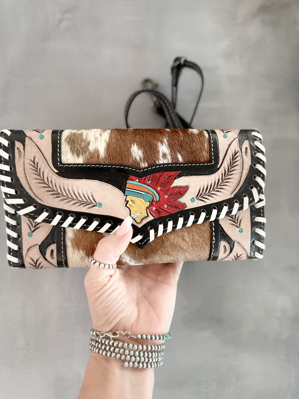 Handmade hair on cowhide and tooled leather clutch with hand painted Indian head centerpiece and feather tooling