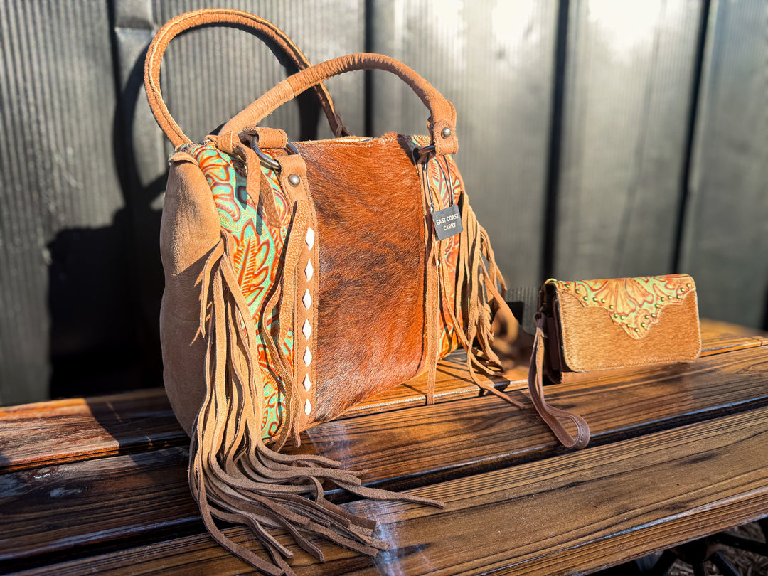 Brindle Brown Cowhide concealed carry leather handbag with fringe and matching wallet on a wooden surface