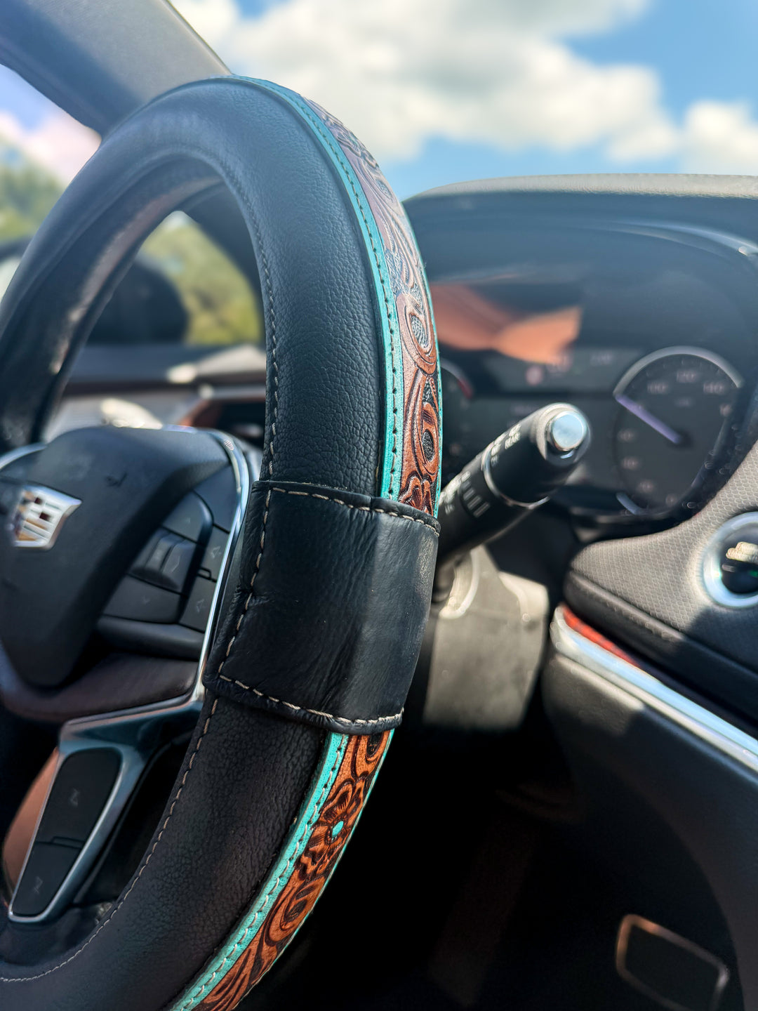 Black and turquoise tooled genuine leather Western steering wheel cover in vehicle interior