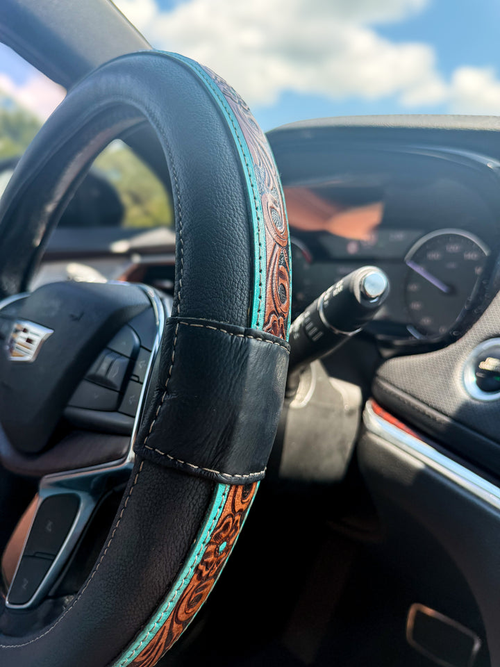 Black and turquoise tooled genuine leather Western steering wheel cover in vehicle interior