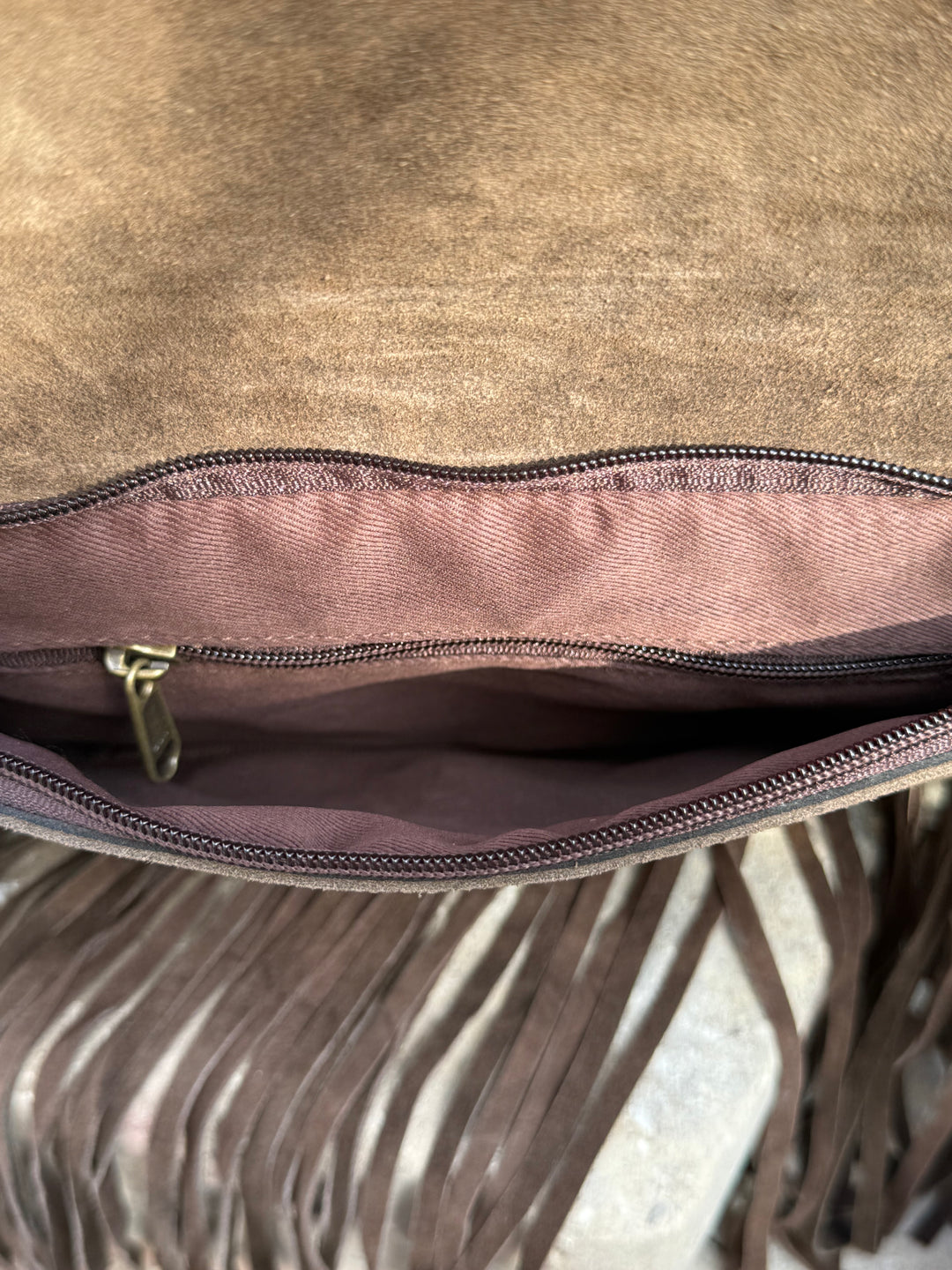 Close-up of a brown leather bag with fringe details