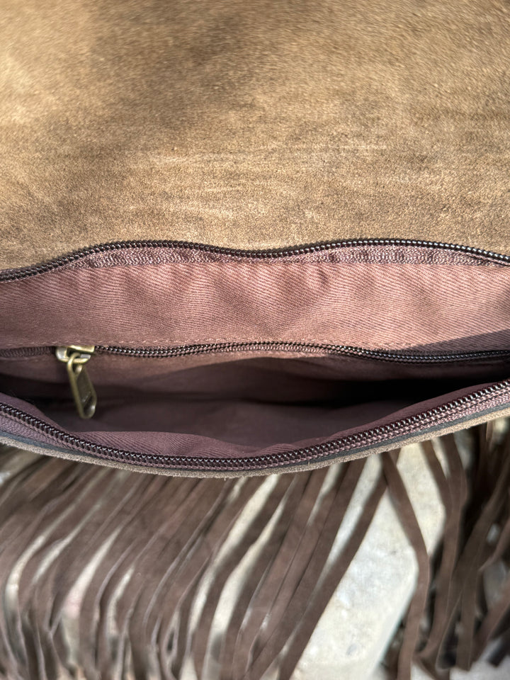 Close-up of a brown leather bag with fringe details