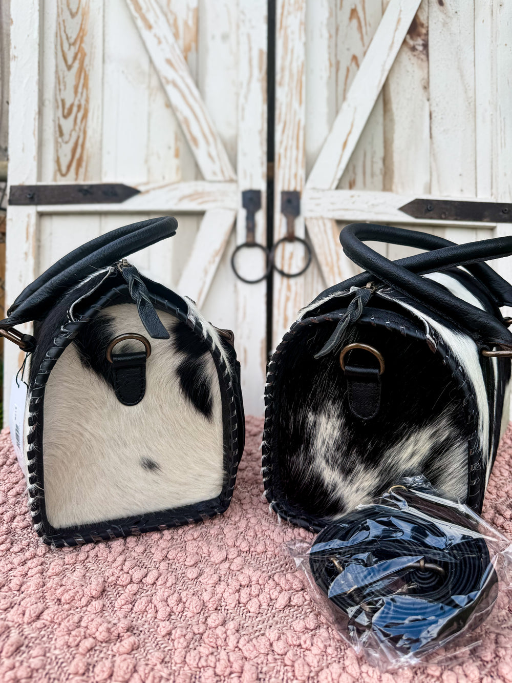 Cowhide leather carryall bag with structured speedy style shape, black and white hair on cowhide, dual handles and detachable leather crossbody strap